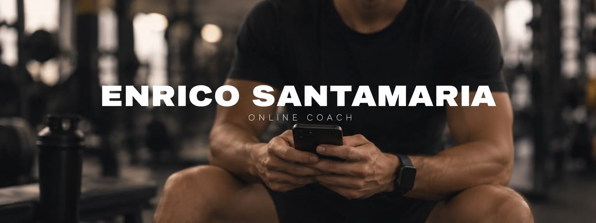 Enrico Santamaria, online coach, seduto in sala pesi con il telefono in mano
